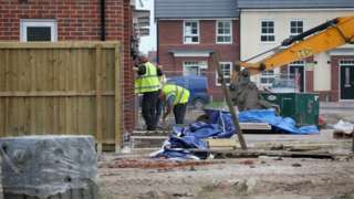 Construction workers build new houses on a housing development in England