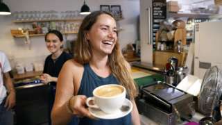 Mulher segurando xícara de café em cafeteria