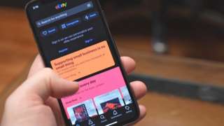 A hand scrolling the eBayv mobile app