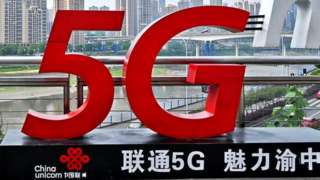 A woman stands beside a China Unicom 5G sign in Chongqing, China.