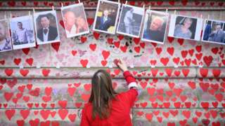 Woman writes on Covid memorial wall in London