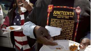 A man in a Juneteenth shirt holds a plate