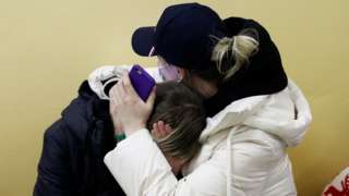 People from Ukraine comfort each other at a refugee shelter