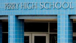A photo from 4 January shows a medical examiner entering Perry High School as police respond to a school shooting