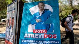 A man walks past an electoral poster of Chilean presidential candidate for the Republican Party, Jose Antonio Kast, in Santiago, November 09, 2021.