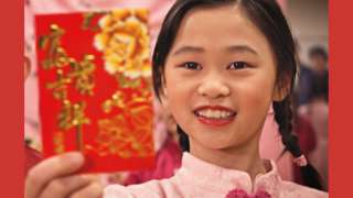Young girl holding up a red envelope