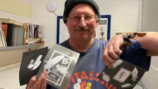 Justin Quinnell holding up photographs