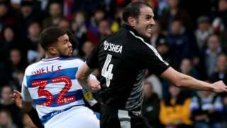 Nahki Wells and John O'Shea challenge in the air