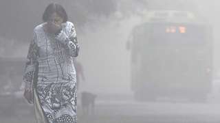 A women covers her face with her hands as she walks amid heavy smog in the early morning at Mayur Vihar area, on November 2, 2016 in New Delhi, India.