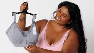 Woman in underwear holding up a bra with NHS messaging on