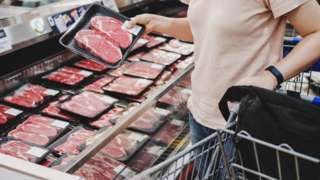 Woman shopping at meat section in supermarket.
