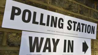 A sign on a wall points to the entrance of a polling station for the London mayoral elections