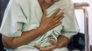 Una mujer en un hospital con la mano en el pecho