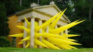 A yellow inflatable artwork with spikes is seen bursting through the pillars of the Temple of Piety at Studley Royal