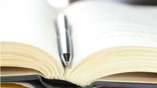 Closeup view of open book with pen