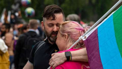 Image shows two protesters embracing