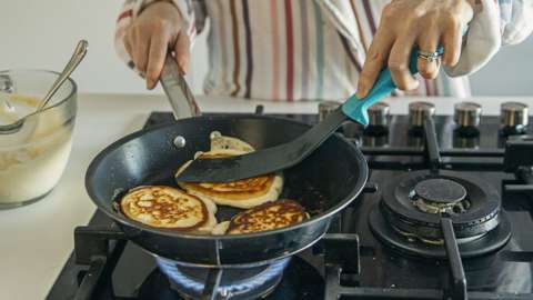 Woman cooking pancakes on gas stove