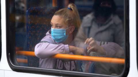 A woman on a bus wearing a face mask