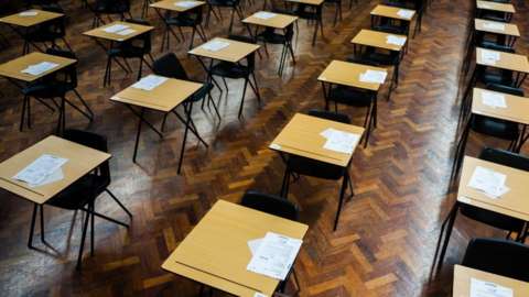 Rows of tables and chairs in a school exam hall