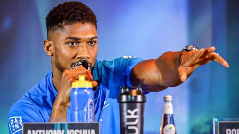Anthony Joshua speaks on a microphone