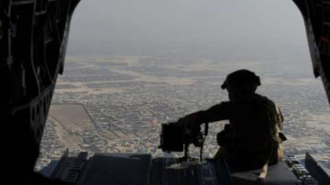 US soldier sits in the rear of Chinook helicopter while flying over Kabul on 10 August 2017