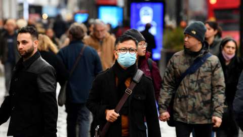 A shopper wearing a protective face mask walks on Oxford Street, as rules on wearing face coverings in some settings in England are relaxed, amid the spread of the coronavirus disease (COVID-19) pandemic, in London