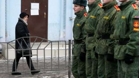 A woman walks past cadets of the self-proclaimed Donetsk People"s Republic