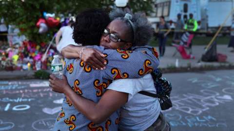 Mourners support each other while visiting a makeshift memorial outside of Tops market on May 15, 2022 in Buffalo, New York.