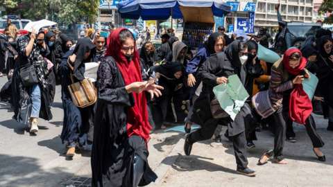Women protesters in Kabul running away from Taliban fighters after they have been beaten and dispersed.