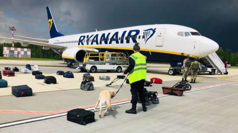 The diverted Ryanair flight sitting on hte ground in Minsk airport as security staff and sniffer dogs check luggage
