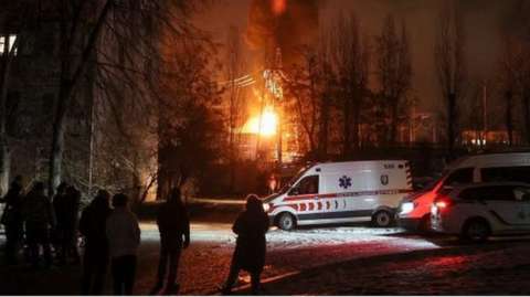 Local residents gather near a residential building as a critical power infrastructure object burns after a Russian drone attack, amid Russia's attack on Ukraine, in Kyiv, Ukraine December 19, 2022.