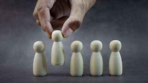 A hand removes one wooden figure from a set of five