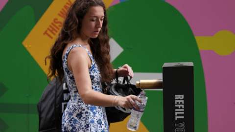 A woman refills a water bottle in the King's Cross area.