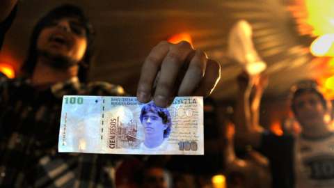 A member of the Maradonian Church The hand of God, a religion dedicated to the Argentina's greatest ever soccer player Diego Maradona, shows a fake one hundred pesos bill during their Christmas celebration in October 2008
