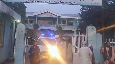 Taliban fighters and medical staff stand outside the gate of an hospital as they prepare to attend to the casualties after an explosion at Imam Sahib district in Kunduz province on April 22, 2022