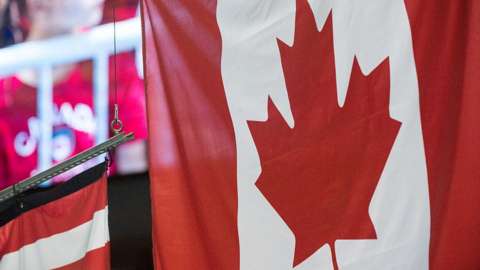 A Canada flag being hoisted during a gymnastics medal ceremony