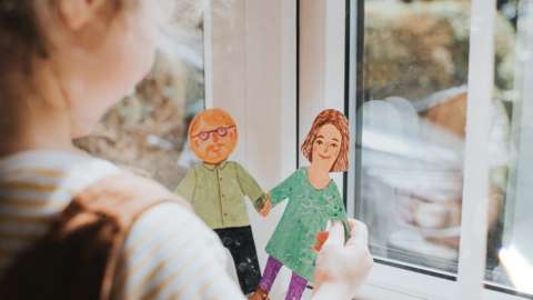 Young girl holding paper dolls of mum and dad