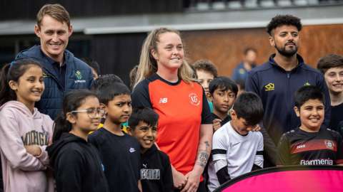 Marnus Labuschagne (left), Georgia Hennessy (centre) and Prem Sisodiya (right) with children at a community event in Grangetown, Cardiff