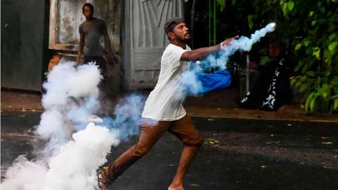 A demonstrator throws back a tear gas canister fired by police to disperse students taking part in an anti-government protest demanding the resignation of Sri Lanka's President Gotabaya Rajapaksa over the country's crippling economic crisis, in Colombo on 29 May, 2022.