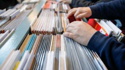 A person looks through vinyl records in a shop