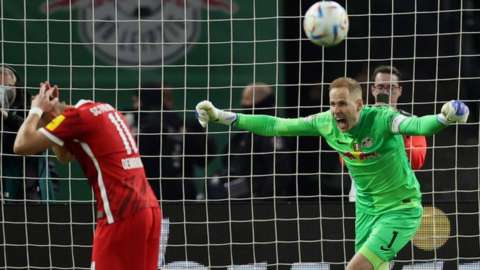 Peter Gulacsi of RB Leipzig celebrates after Ermedin Demirovic of Freiburg missed the decisive penalty in the shoot-out