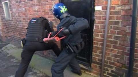 Police officers battering a door down