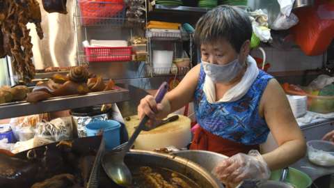 Lim Bee Hong preparing food at her small food stall in Singapore, April 21, 2020