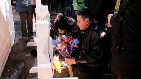 A man lays flowers during a candlelight vigil in Waukesha