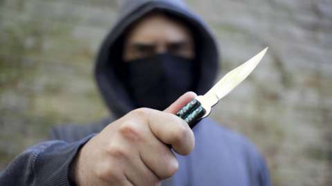 A hooded youth brandishes a knife