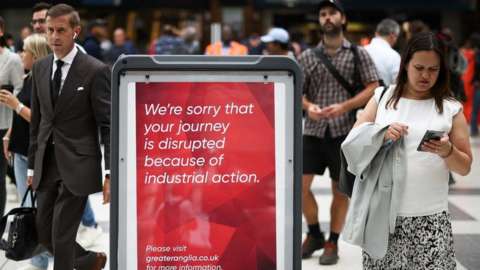 People walk past information signs inside Liverpool Street station in London