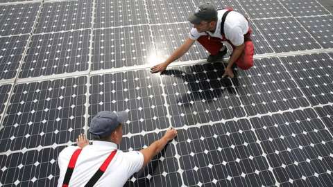 Workers install solar panels in Germany