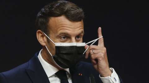 France's President Emmanuel Macron takes off his facemask before giving a press conference during the European Social Summit hosted by the Portuguese presidency of the Council of the European Union at the Palacio de Cristal in Porto on May 8, 2021