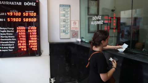 A woman exchanges money at a currency exchange office in Istanbul, Turkey.