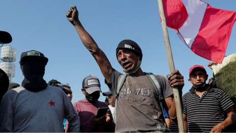 A man holding the flag of Peru with his fist in the air